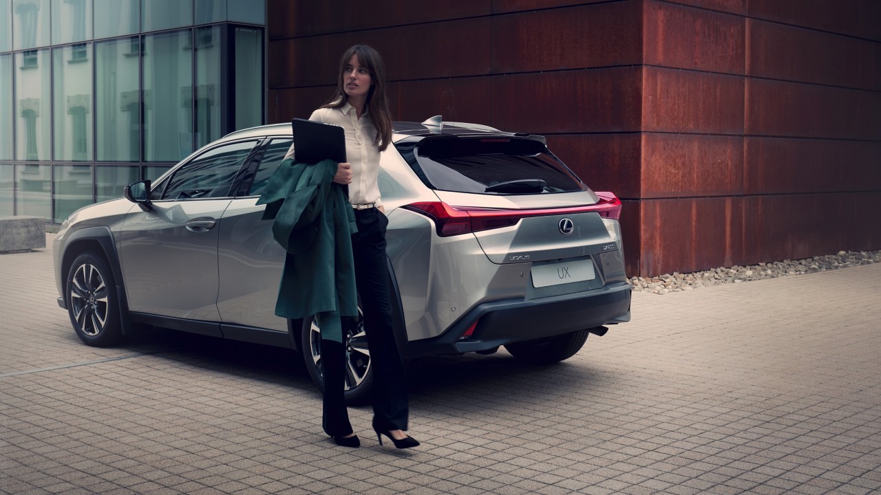 woman standing outside next to a Lexus UX
