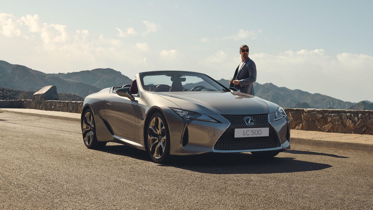 person standing next to the Lexus LC Convertible on a road