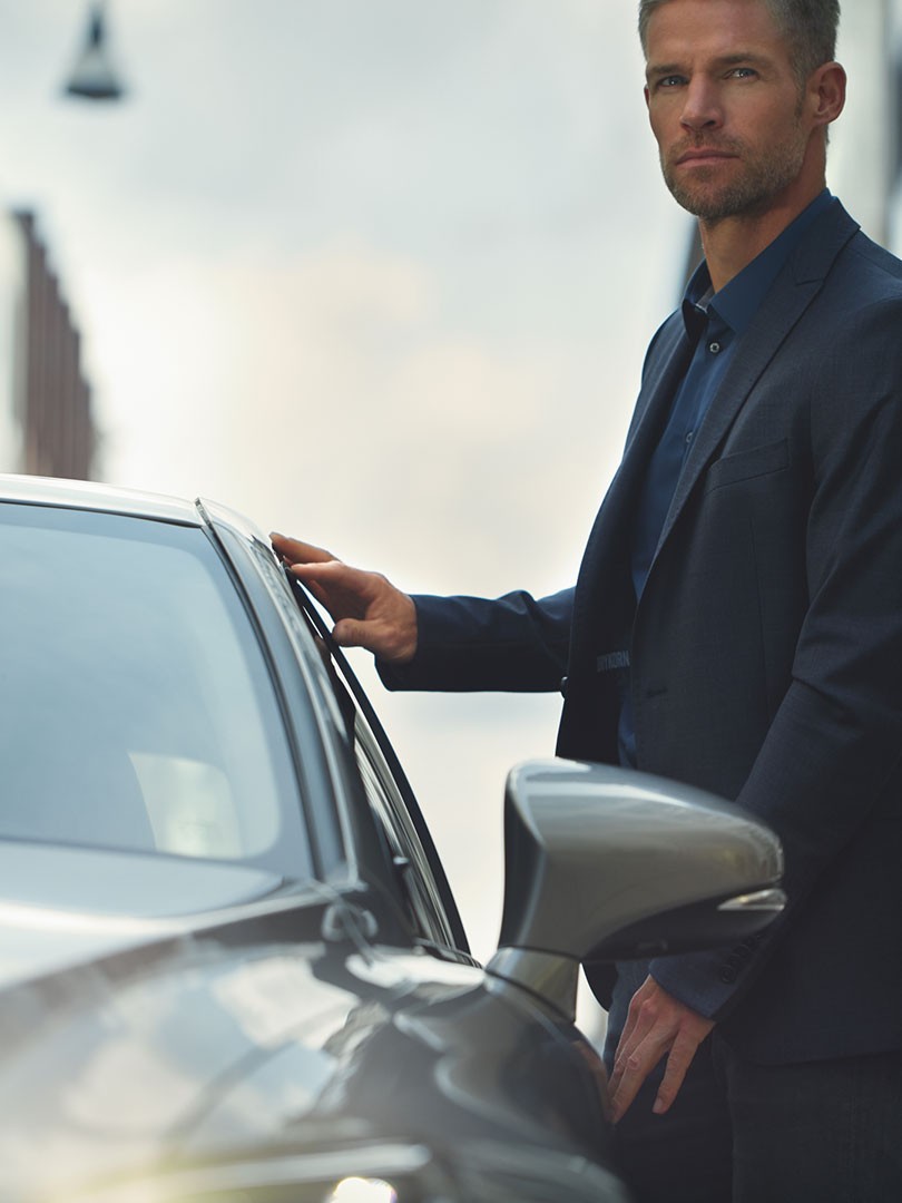 man standing next to a Lexus car