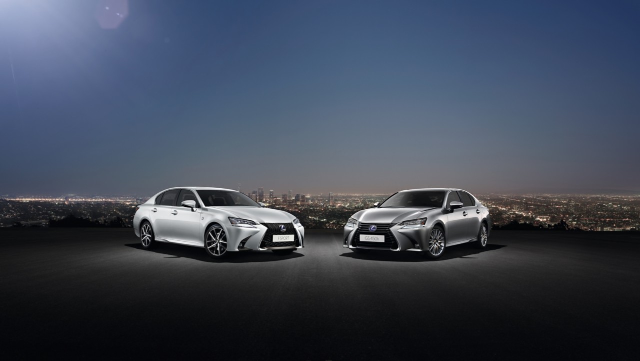 two Lexus GS cars parked with a city background