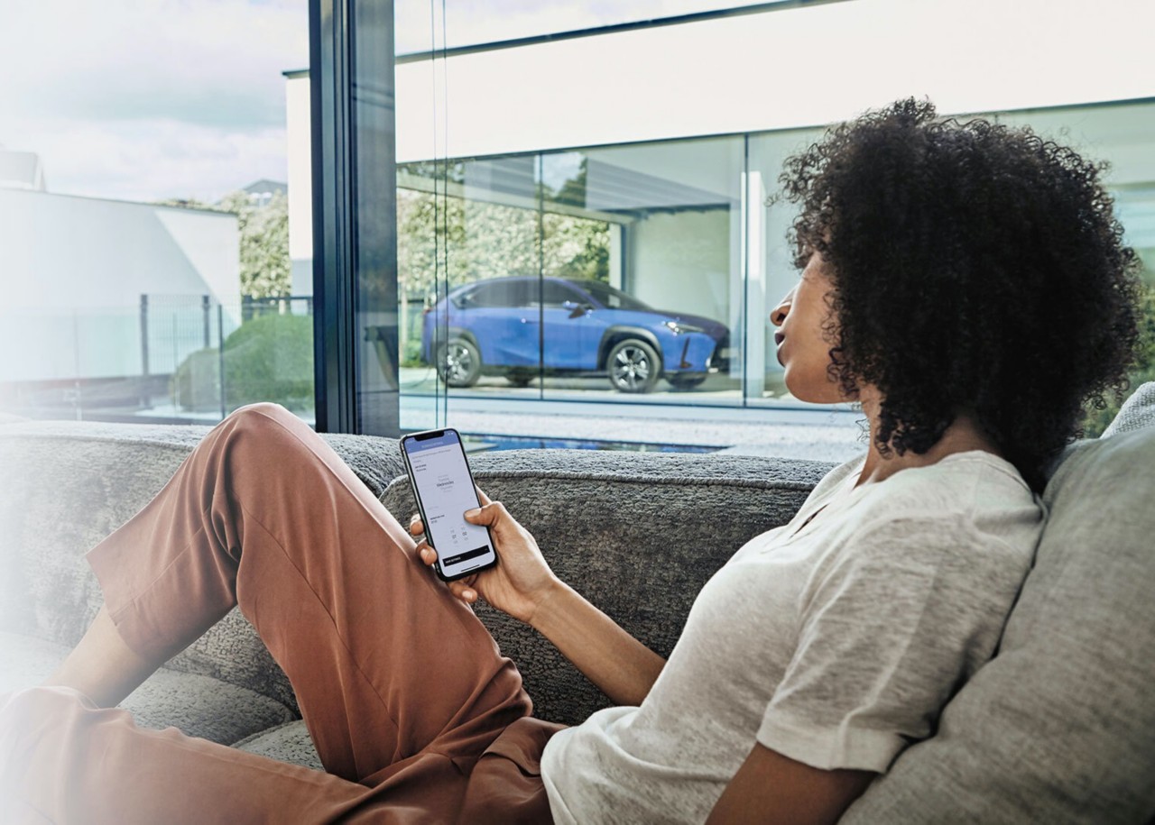 woman looking at her phone with a Lexus car in the background