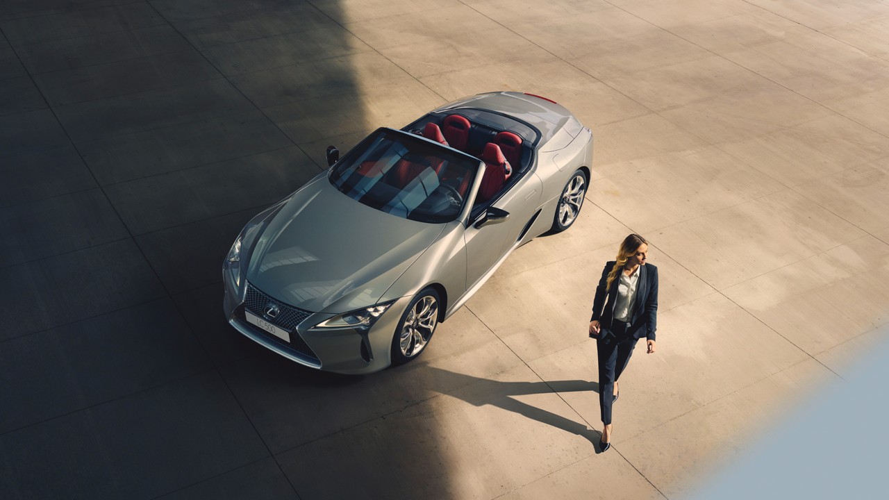 A woman walking away from a parked Lexus Convertible